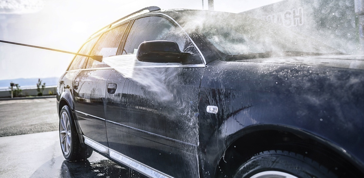 A black car being hand-washed with a pressure washer